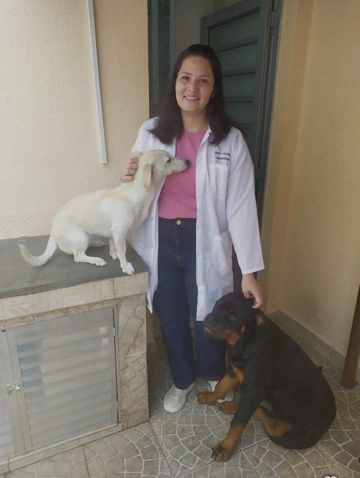 Dra. Oriana com dois cachorros na porta de uma casa
